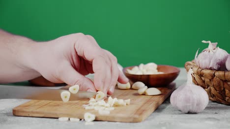 men's hands cut the garlic into pieces on a wooden cutting board.