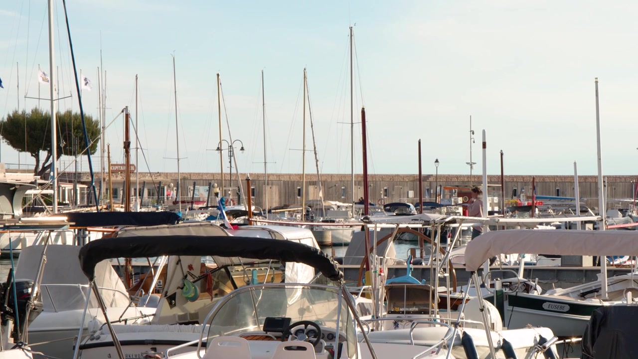 Statische Weitwinkelaufnahme zahlreicher weißer Boote, die in einem sonnigen französischen Hafen mit Leuchtturm vertäut sind