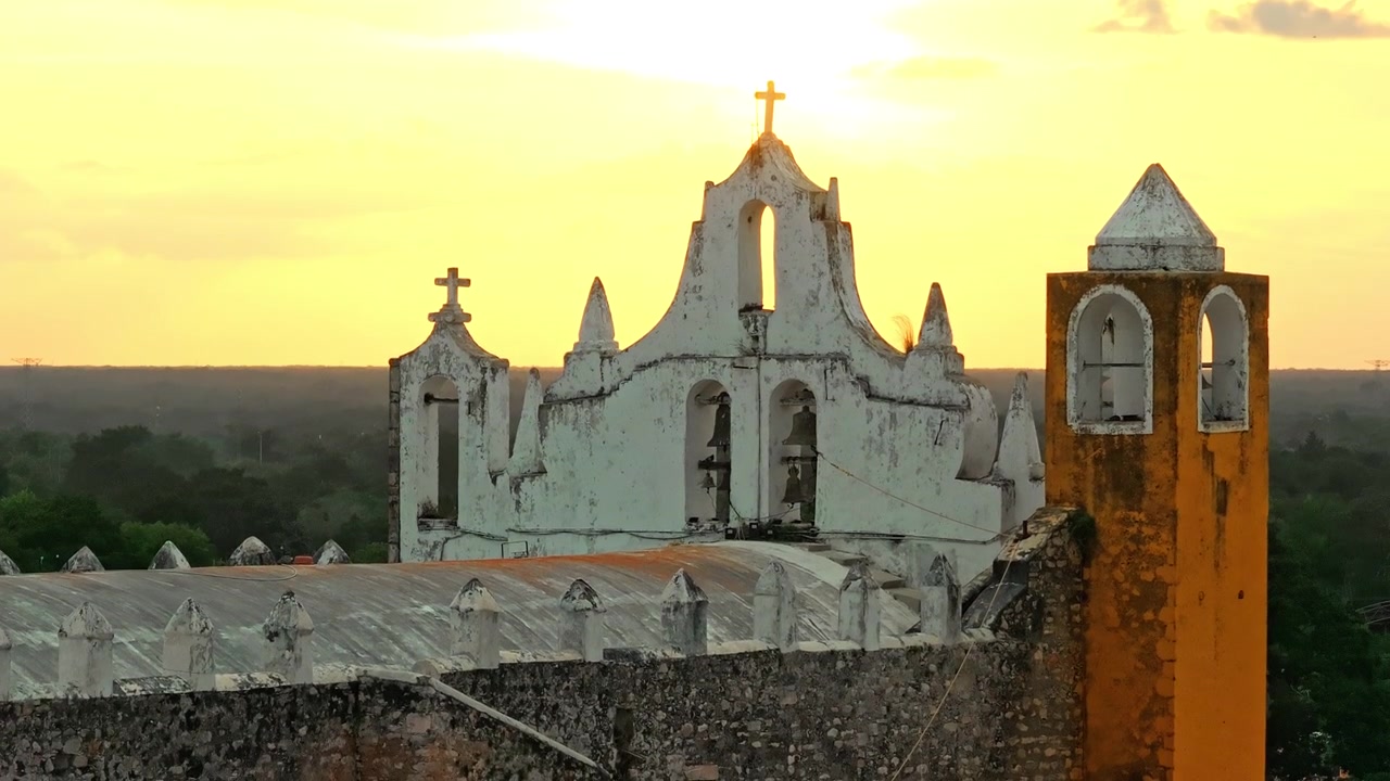Veduta aerea della chiesa di Izamal stagliata contro un cielo al tramonto luminoso nello Yucatán, Messico, la Città Gialla che svanisce nel crepuscolo tropicale.