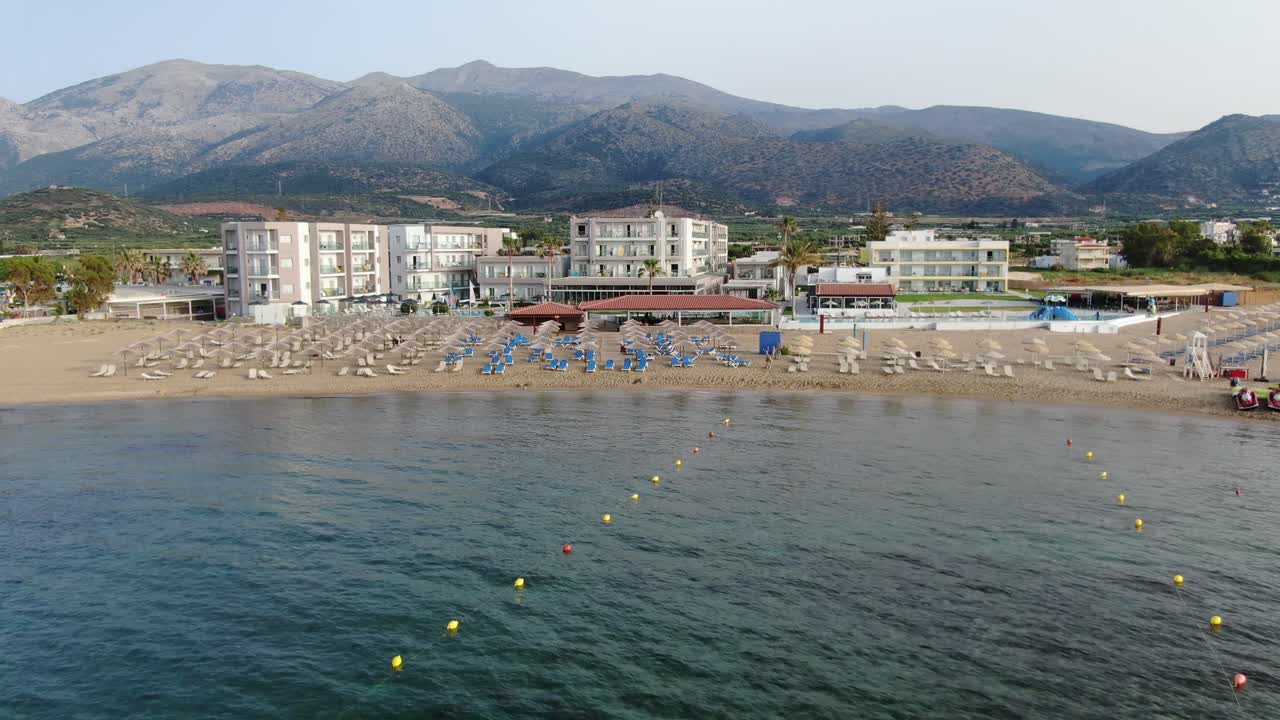 turista bajo sombrilla en la concurrida playa griega, hermosas aguas turquesas y azules
