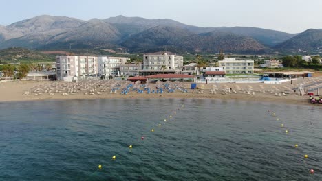 tourist under parasol on crowded greek beach, beautiful turquoise and blue water