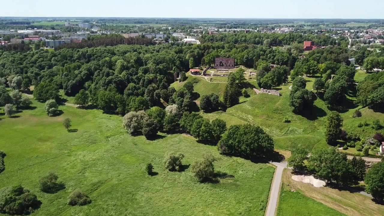 Splendida vista aerea con drone delle famose colline del castello storico e del lussureggiante paesaggio verde del parco estivo che circonda l'area del lago a Viljandi.