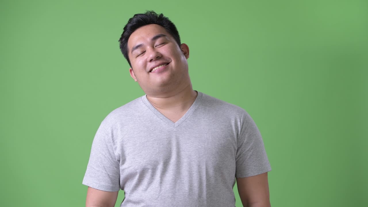 초록색 배경에 젊은 잘생긴 과체중 아시아인