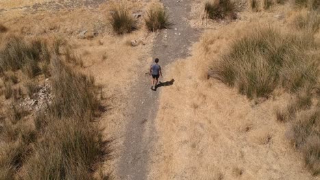 person running through arid brown field from aerial view with drone