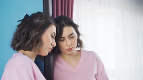 unhappy and depressed young woman looking in mirror.