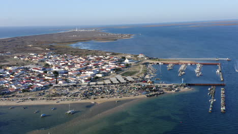 Muelle-De-La-Isla-De-Culatra-Junto-Al-Mar-Azul-Tranquilo-Con-Ciudad-Costera-En-Verano-En-Portugal