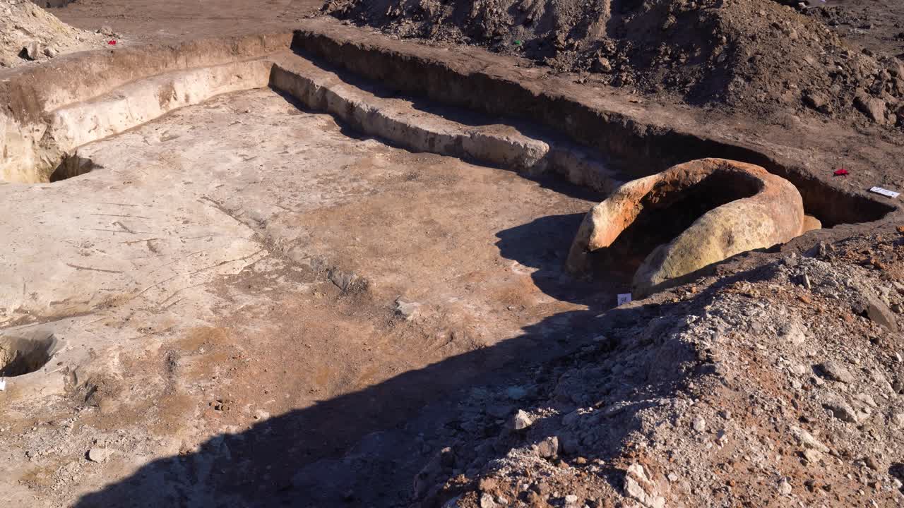 Slow pan looking down into large rectangle pit at archaeology site