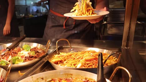 hand serving noodles at food market stall