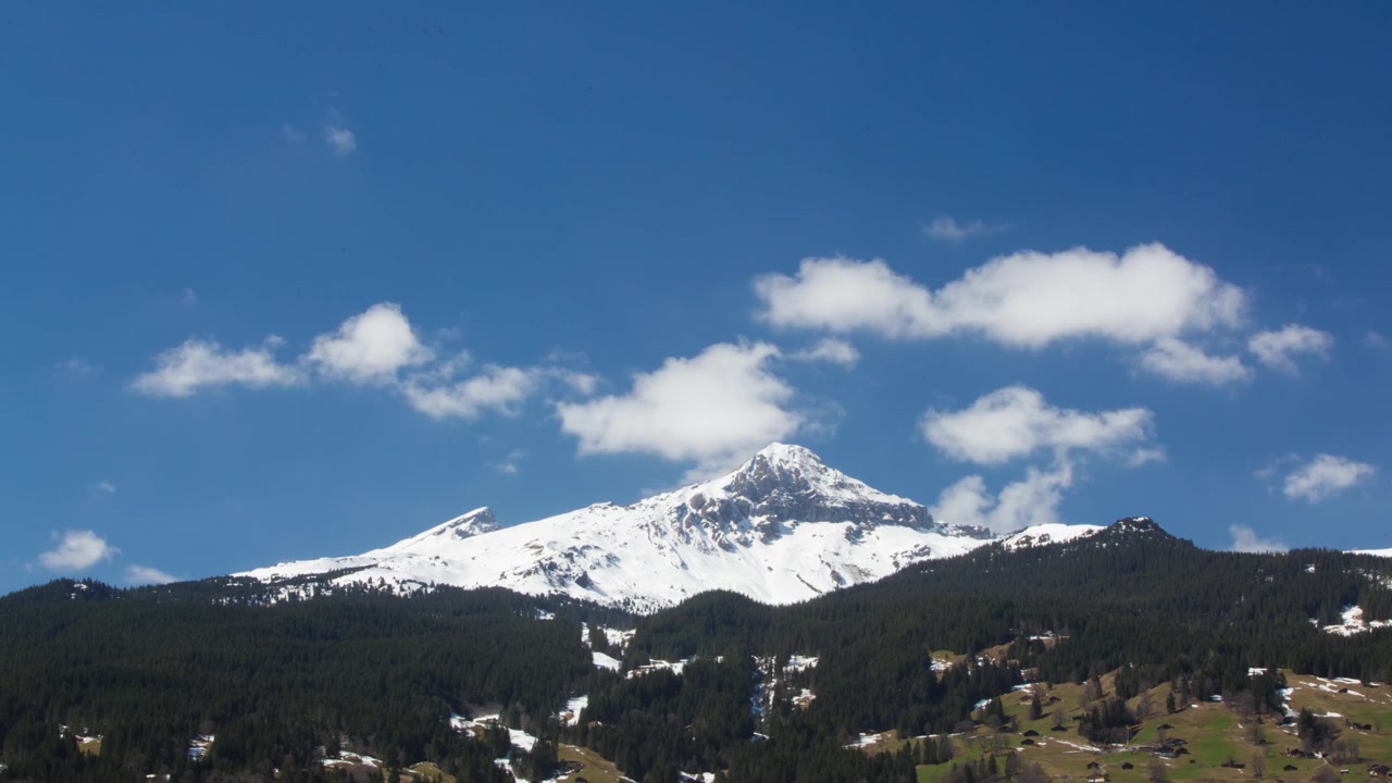 Timelapse di nuvole cumuliformi sopra la cima di una montagna innevata a Grindelwald, Svizzera.