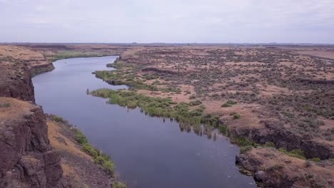 western sagebrush flyover of scablands pond to kayakers in distance