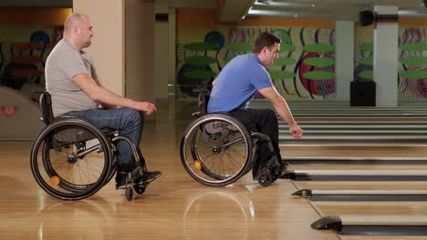 two young disabled men in wheelchairs playing bowling in the club