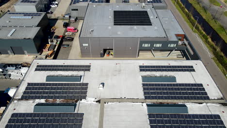 Low-aerial-of-solar-panels-on-warehouses-on-busy-industrial-terrain