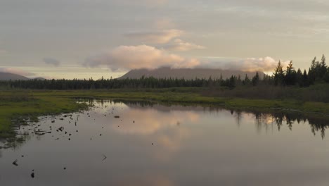 Aerial-flight-flat-calm-reflective-water-showing-wilderness-sunrise-mountain-scenery