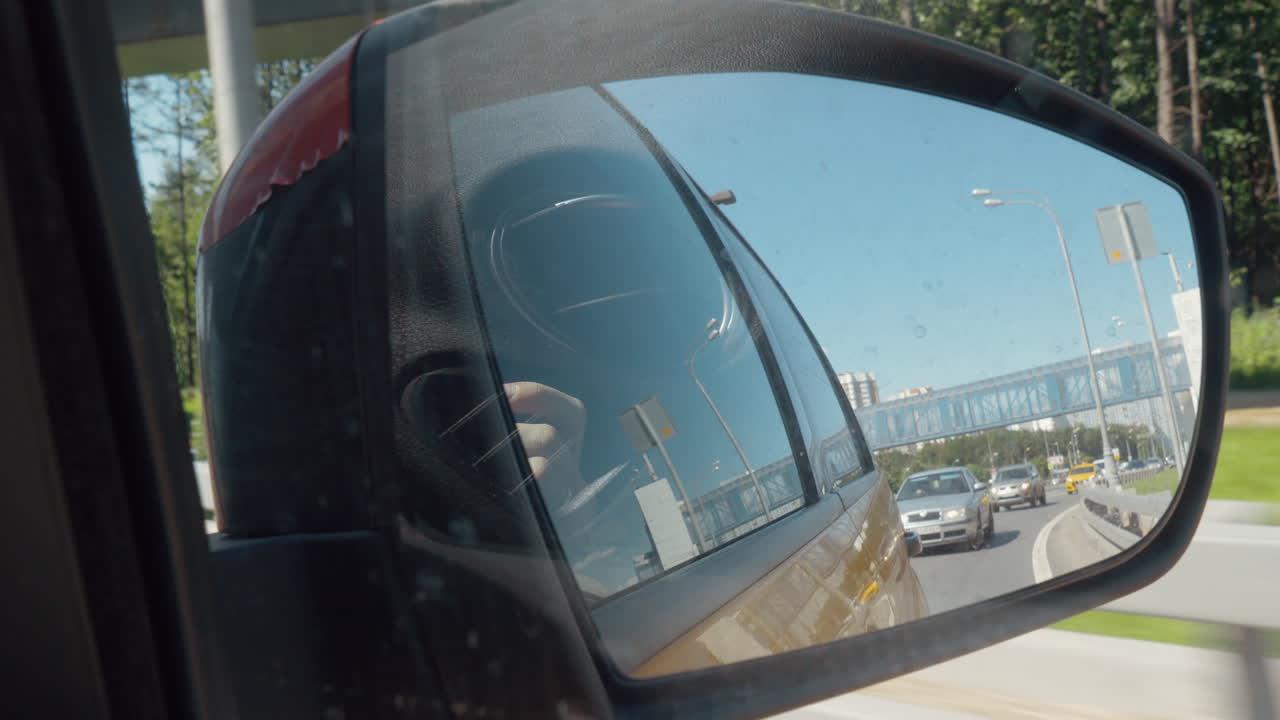 Vista della città e del traffico nel riflesso dello specchietto laterale dell'auto