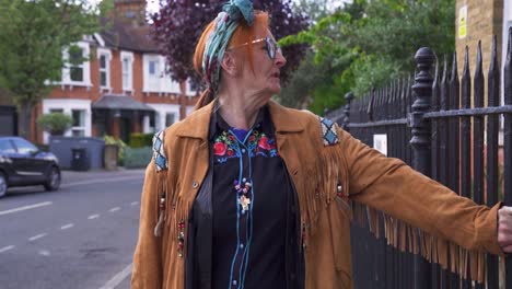 A-modern,-trendy-older-woman-standing-in-the-street-looking-melancholy