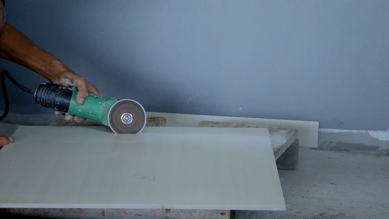 trabajador cortar una baldosa con una amoladora angular en el sitio de construcción