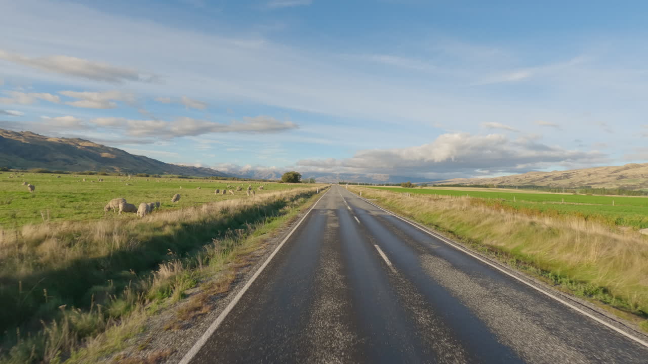 Veículo trafegando em uma rodovia de duas pistas e passando pela paisagem rural em Otago, Nova Zelândia