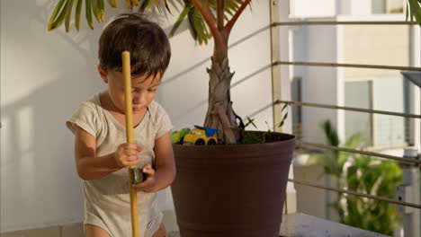 young little latin toddler after a mischief cleaning the floor with a toy broom on a sunny afternoon