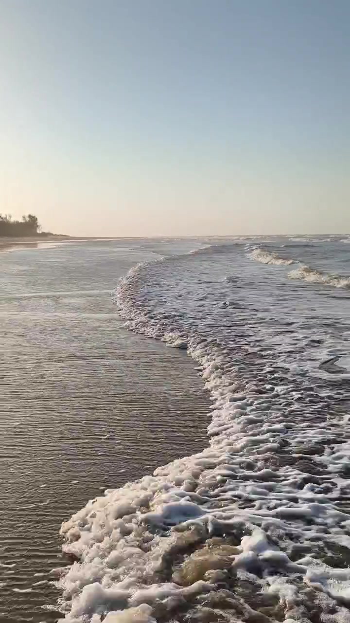 Dolci Onde dell'Oceano che si Infrangono su una Spiaggia Sabbiosa al Tramonto