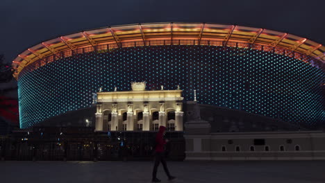 illuminated stadium at night with a pedestrian