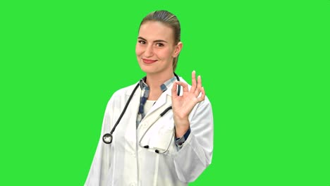 doctora femenina muestra el signo ok mirando a la cámara sonriendo con confianza en una pantalla verde, llave de croma
