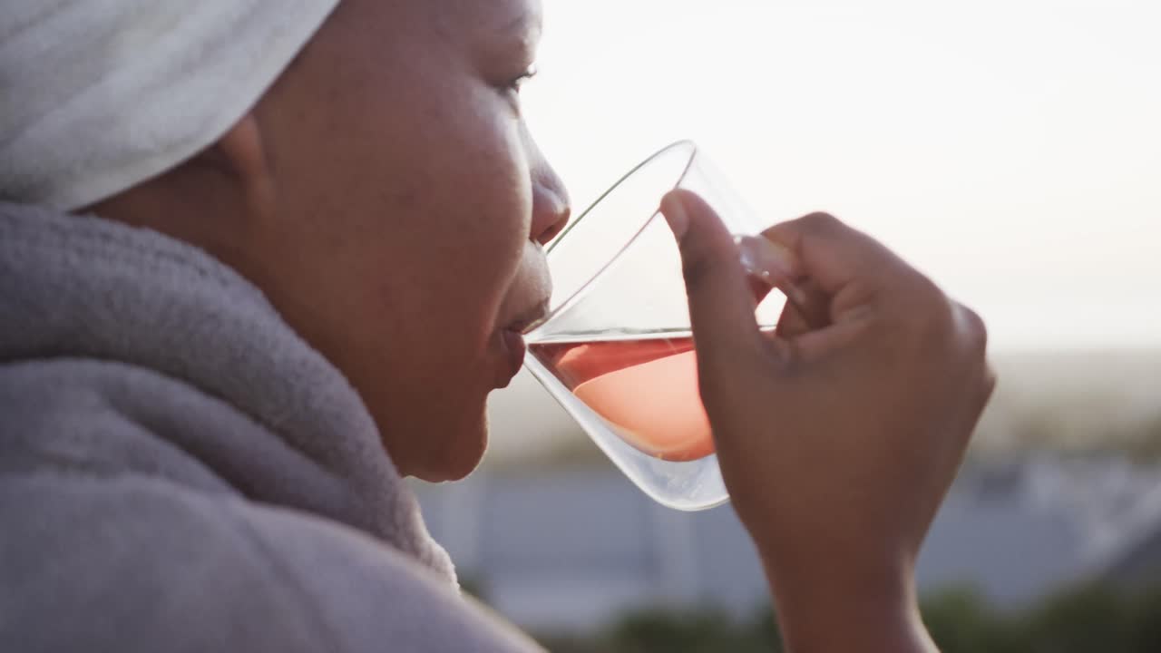 African american plus size woman drinking tea on balcony, unaltered, slow motion