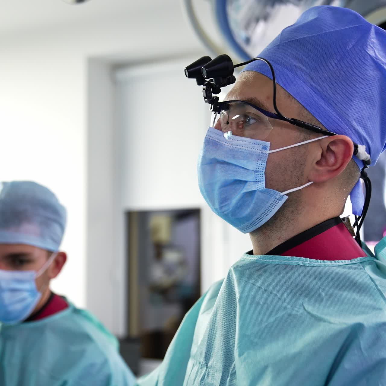 Male doctor in device glasses and mask looks ahead. Portrait of a focused surgeon staring in front of him. Side view
