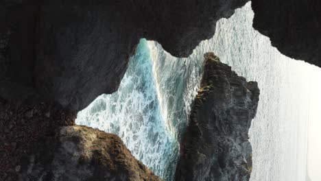 POV-watching-the-waves-between-rocks,-vertical-footage