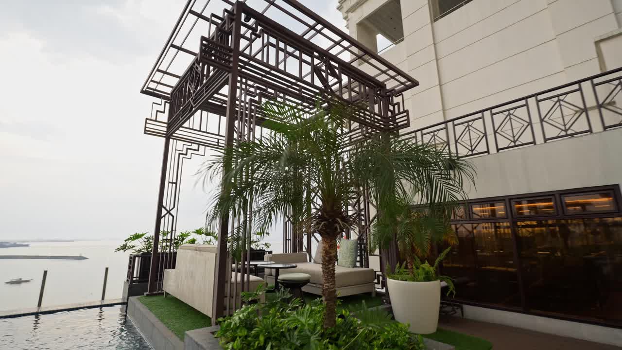 A cinematic view showcases a lavish rooftop terrace, featuring plush seating, ambient lighting, and stunning panoramic views of a clear sky.