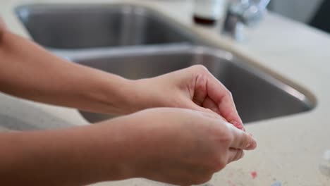 hands slicing and extracting finger lime pulp on a countertop with a sink in the background