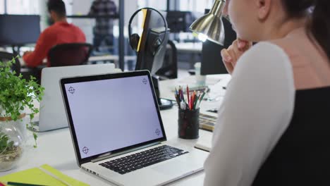 Caucasian-businesswoman-sitting-at-desk-using-laptop-with-copy-space