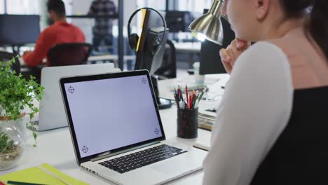 mujer de negocios caucásica sentada en un escritorio usando una computadora portátil con espacio de copia