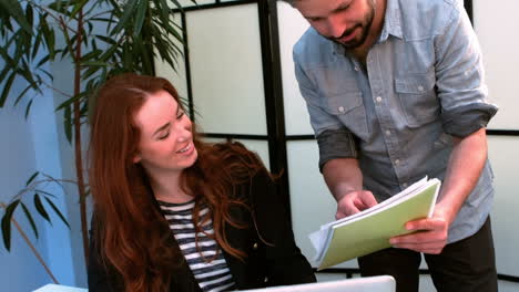 Business-executives-discussing-over-document-while-using-laptop