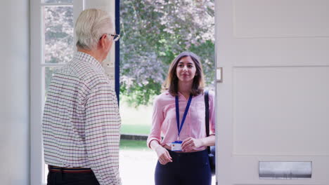 senior man opens front door to young woman making home visit