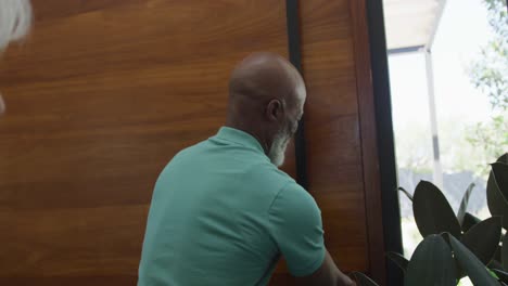 gelukkige oudere afro-amerikaanse man die de deur opent bij een bejaardentehuis