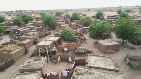 drone spirals sideways over a rural village with earthen homes in nigeria during daytime, capturing daily life and unique architecture from above