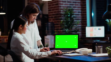 Coworkers-looking-over-accounting-figures-on-chroma-key-laptop