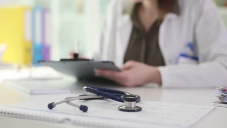 a doctor working at a desk with a stethoscope in the foreground