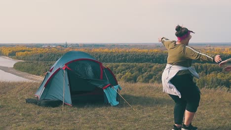 tipsy-girls-hug-on-meadow-at-tent-against-autumn-forests