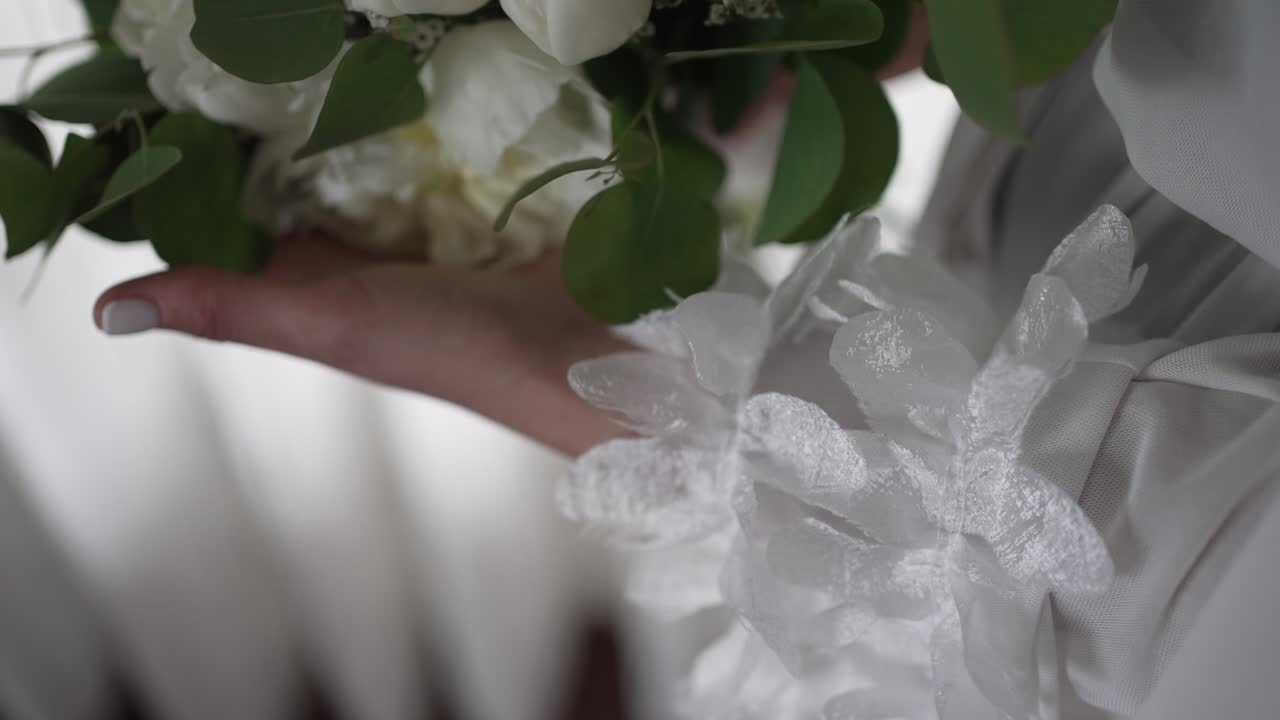 buquê de noiva de rosas brancas delicadamente segurado com detalhes de folhagens