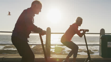 Senior-couple-using-electronic-scooters-alongside-beach