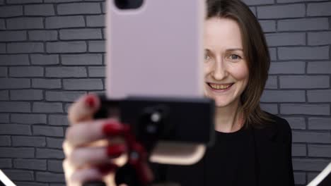 blogger woman shooting story with ring lamp on brick wall background