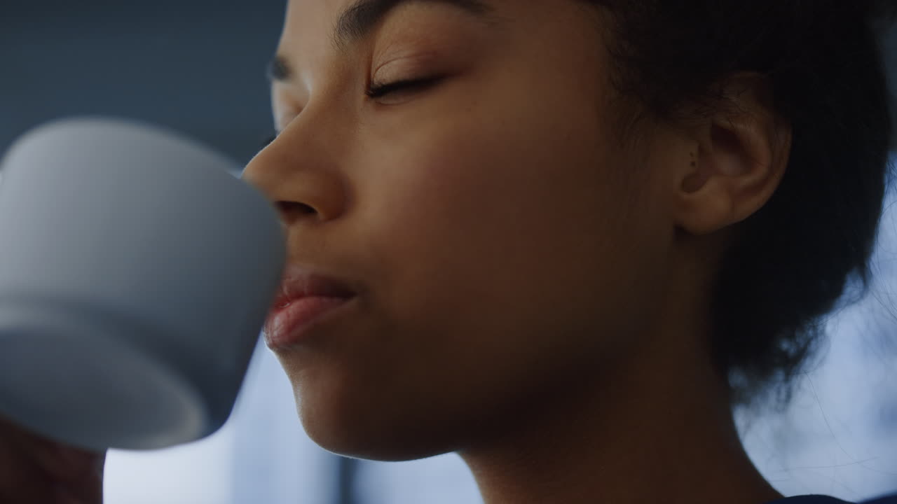 African woman drinking coffee cup in office. Professional enjoying coffee