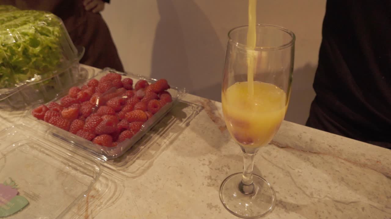 Succo di frutta appena fatto versato in un bicchiere accanto a delle fragole sul ripiano di una cucina