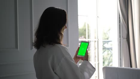 mujer en bata de baño usando teléfono con pantalla verde