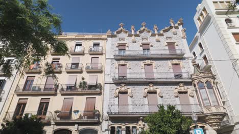 low angle view of residential buildings with ornate stone facades and balconies, showcasing modernist architecture in tarragona, spain