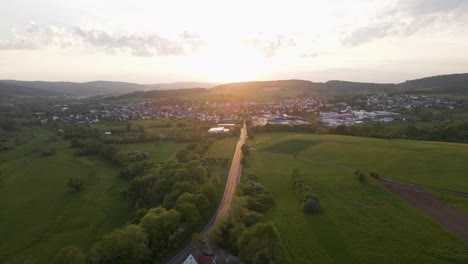 three cars headed towards a village underneath an epic sunset in germany's countryside