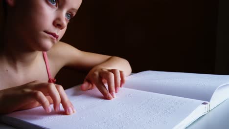 schoolgirl reading a braille book in classroom