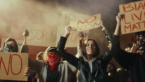 lower view of caucasian woman yelling and holding a no racism" signboard in a protest with multiethnic group of people in the street"