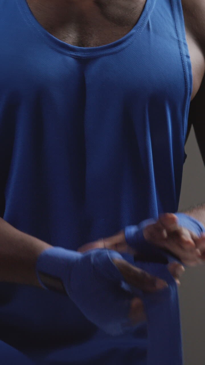 Vertical Video Close Up Of Male Boxer Wrapping Hands With Protective Bandages Before Boxing Match Or Training Session